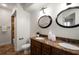 Well-lit bathroom with double sink vanity, granite countertop, decorative mirrors, and tiled shower at 11910 Keating Dr, Tampa, FL 33626