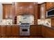 Gourmet kitchen with stainless steel Viking range, custom wood hood, tile backsplash and wood cabinets at 11910 Keating Dr, Tampa, FL 33626