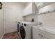 Clean and functional laundry room equipped with white washer, dryer, sink, and storage cabinets at 11910 Keating Dr, Tampa, FL 33626