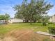 Backyard with ample lawn space framed by mature trees and complex buildings at 129 Cypress Ct, Oldsmar, FL 34677