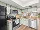 The kitchen features light-green cabinets, stainless steel appliances and wood-look flooring at 129 Cypress Ct, Oldsmar, FL 34677
