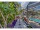 Tropical backyard oasis featuring a screened-in pool, lush landscaping, and stone walkway at 14073 Jennifer Ter, Largo, FL 33774