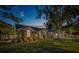 Twilight view of a well-manicured lawn with lovely landscaping and exterior lighting at 14073 Jennifer Ter, Largo, FL 33774