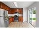 Spacious kitchen featuring stainless steel appliances, wood cabinets, and sliding door access to the patio at 1506 Lenton Rose Ct, Trinity, FL 34655