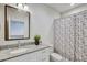 Well-lit bathroom featuring a granite vanity, white cabinetry, and a shower with decorative curtain at 1510 Blue Sea St, Clearwater, FL 33756