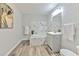 Bright bathroom with gray walls, wood-look flooring, and a tub with marble-look tiled surround at 1511 Meridel Ave, Tampa, FL 33612