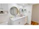 Bright bathroom with marble countertop, double round mirrors, and white shaker-style cabinets at 1849 Del Robles Dr, Clearwater, FL 33764