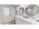 Bright bathroom with marble countertop, double round mirrors, and white shaker-style cabinets at 1849 Del Robles Dr, Clearwater, FL 33764