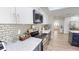 A well-lit kitchen boasts white cabinets, stainless steel appliances, and beautiful tile backsplash at 1849 Del Robles Dr, Clearwater, FL 33764