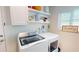 Bright laundry room with white washer, dryer, storage shelves, decor and a window at 1849 Del Robles Dr, Clearwater, FL 33764