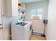 Cozy laundry room with white washer, dryer, storage shelves and a sign reading 