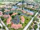 Aerial view of condominiums with red tile roofs, lush landscaping, and a nearby lake at 21012 Picasso Ct # 201, Land O Lakes, FL 34637