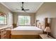 Cozy bedroom featuring wood-trimmed bed, dresser, and views of lush greenery outside at 21012 Picasso Ct # 201, Land O Lakes, FL 34637