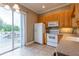 Bright kitchen featuring a sliding glass door, white appliances, and wood cabinets at 21012 Picasso Ct # 201, Land O Lakes, FL 34637