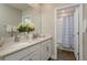 Bright bathroom with double sinks, white cabinets, a large mirror, and a shower with a blue curtain at 21590 Violet Periwinkle Dr, Land O Lakes, FL 34637