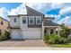 Two-story home featuring a paved driveway leading to a two-car garage, landscaped yard, and modern architectural details at 21590 Violet Periwinkle Dr, Land O Lakes, FL 34637