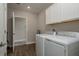 Laundry room with white cabinets, washer, dryer and wood-look tile flooring at 21590 Violet Periwinkle Dr, Land O Lakes, FL 34637