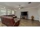 Spacious living room featuring a brown leather sofa, a decorative globe, and stylish wood-look tile flooring at 21590 Violet Periwinkle Dr, Land O Lakes, FL 34637