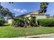 A low angle view of the house with green grass, bushes, and palm trees in a sunny weather at 2600 Forest Run Ct, Clearwater, FL 33761