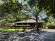 View of the community clubhouse with lush landscaping and a brick walkway leading up to the front entrance at 404 Lennox W Rd # 404, Palm Harbor, FL 34683