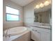 Bathroom featuring a large soaking tub, granite vanity, and tile surround, bathed in natural light at 4730 Wandering Way, Wesley Chapel, FL 33544