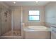 Bright bathroom featuring a glass-enclosed shower and a luxurious soaking tub with stone tile accents at 4730 Wandering Way, Wesley Chapel, FL 33544