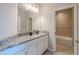 A modern bathroom features granite countertops, white cabinetry, a sink, and access to a shower-tub combo at 4730 Wandering Way, Wesley Chapel, FL 33544