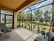 A covered lanai with a view of the yard, featuring plants and outdoor seating at 4730 Wandering Way, Wesley Chapel, FL 33544