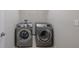 A laundry room features side-by-side silver washer and dryer units, with a shelf above for supplies at 4730 Wandering Way, Wesley Chapel, FL 33544