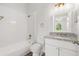 This bathroom features a white vanity with granite counters and tub with white tiled walls and gold fixtures at 5084 Misty Canal Pl, Bradenton, FL 34203
