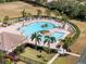 Aerial view of a large community pool with palm trees, lounge chairs, and a clubhouse at 5084 Misty Canal Pl, Bradenton, FL 34203