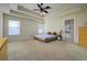 Spacious main bedroom featuring a tray ceiling, carpet, and ensuite bathroom at 6216 Evansbrook Dr, Zephyrhills, FL 33541