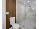 Stylish bathroom featuring a glass enclosed shower with gold fixtures, and modern toilet with wood slat wall at 6321 Balboa Ln, Apollo Beach, FL 33572