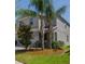 Two-story home with a neutral color scheme, complemented by mature palm trees and green lawn at 6707 Blue Moon Way, Sun City Center, FL 33573