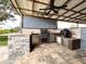 Outdoor kitchen featuring a built-in grill, smoker, stainless steel appliances, stone countertops, and a ceiling fan at 812 Jameson Rd, Lithia, FL 33547