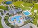 Aerial view of community pool area with pool, waterslide, ample parking and a pond at 8717 Emeraldwood Way, Land O Lakes, FL 34637