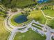 Aerial view of a beautiful community pond surrounded by lush greenery and walking paths at 8717 Emeraldwood Way, Land O Lakes, FL 34637