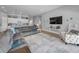 Open-concept living room featuring a gray sectional sofa, television, and view into the open kitchen at 8717 Emeraldwood Way, Land O Lakes, FL 34637