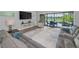 Bright living room featuring a gray sectional sofa, television, and views of the outdoor pool area through large sliding glass doors at 8717 Emeraldwood Way, Land O Lakes, FL 34637