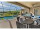 Spacious screened patio featuring comfortable seating, a dining area, and a view of the serene pool and lush backyard at 8717 Emeraldwood Way, Land O Lakes, FL 34637