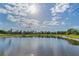 Wide, still pond reflecting the sky, surrounded by green grass and foliage, showcasing a peaceful community space at 8717 Emeraldwood Way, Land O Lakes, FL 34637