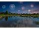 Scenic pond reflecting fireworks and a colorful sunset, surrounded by lush green spaces at 8717 Emeraldwood Way, Land O Lakes, FL 34637