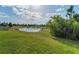 Scenic view of a calm pond surrounded by green grass and mature trees, offering a serene and natural backdrop at 8717 Emeraldwood Way, Land O Lakes, FL 34637