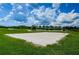 Well-maintained sand volleyball court on a sunny day, surrounded by green grass and mature trees at 8717 Emeraldwood Way, Land O Lakes, FL 34637