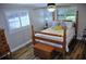 Comfortable bedroom featuring wood floors, a four-poster bed, chest and bright windows with wooden blinds at 915 Rolling Hills Dr, Palm Harbor, FL 34683