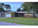 Well-kept single-story home featuring an attached garage, verdant lawn, and mature trees at 915 Rolling Hills Dr, Palm Harbor, FL 34683