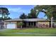 Charming single-story home with a well-maintained lawn, attached garage, and mature landscaping at 915 Rolling Hills Dr, Palm Harbor, FL 34683