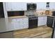 Bright kitchen features white cabinets, stone countertops, stainless steel appliances, and wood flooring at 915 Rolling Hills Dr, Palm Harbor, FL 34683