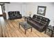 Living room features wood flooring, leather sofas, side tables, and lamps at 915 Rolling Hills Dr, Palm Harbor, FL 34683