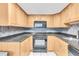 Well-lit kitchen features oak cabinets, black appliances, granite countertops, and stylish backsplash at 1 Key Capri # 303E, Treasure Island, FL 33706